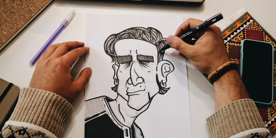 Main d’artiste dessinant à l’encre sur une feuille de papier