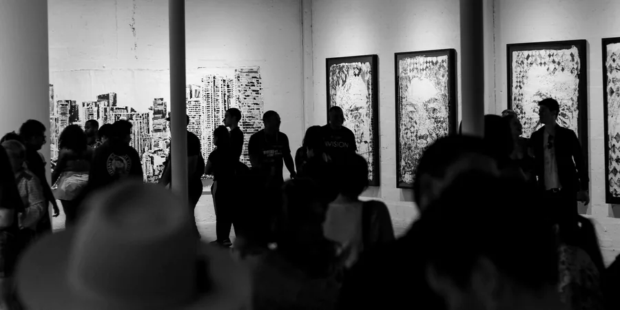 Exposition de jeunes artistes Visiteurs en silhouette devant de grands dessins encadrés lors d’un vernissage