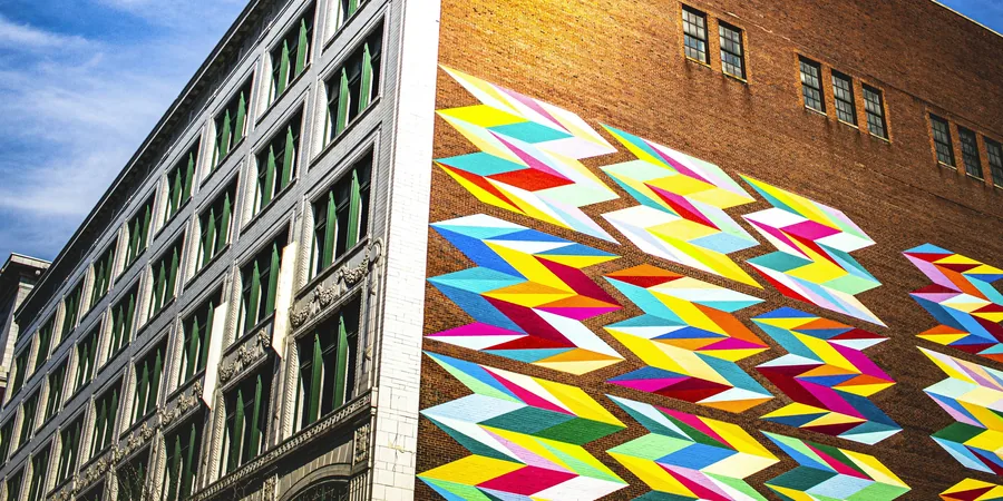 Grande fresque géométrique colorée sur la façade en briques d'un immeuble