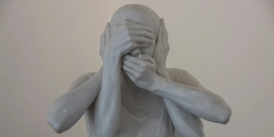 Statue en marbre blanc dont les mains couvrent le visage